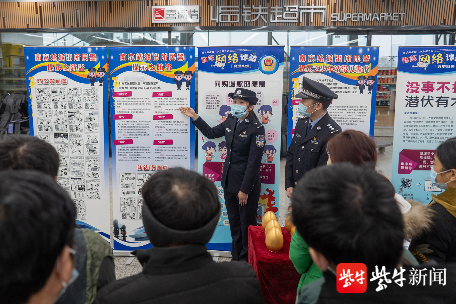 图为南京火车站派出所民警通过防盗防骗宣传展板向旅客宣传安全知识.