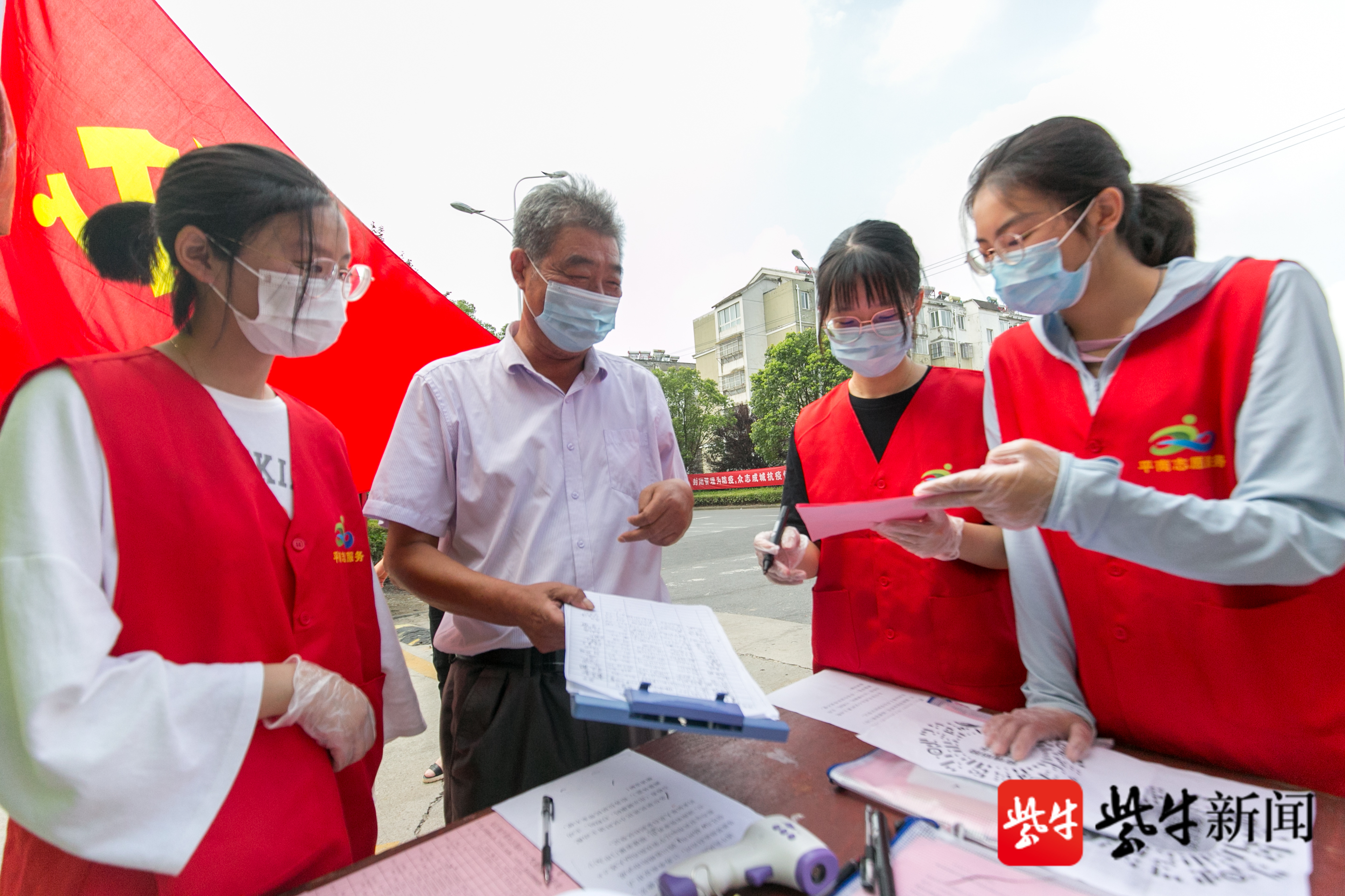 在如皋市长江镇平南社区一疫情防控卡口,大学生志愿者正在为居民办理