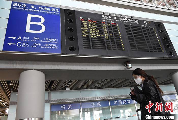 资料图:4月8日,北京首都机场3号航站楼,一名女子经过到达航班信息屏.