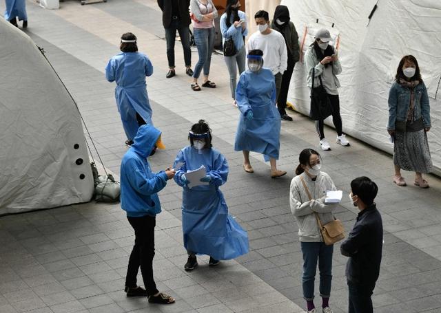 5月12日,在韓國首爾梨泰院一處新冠病毒檢測站,醫護人員引導民眾排隊