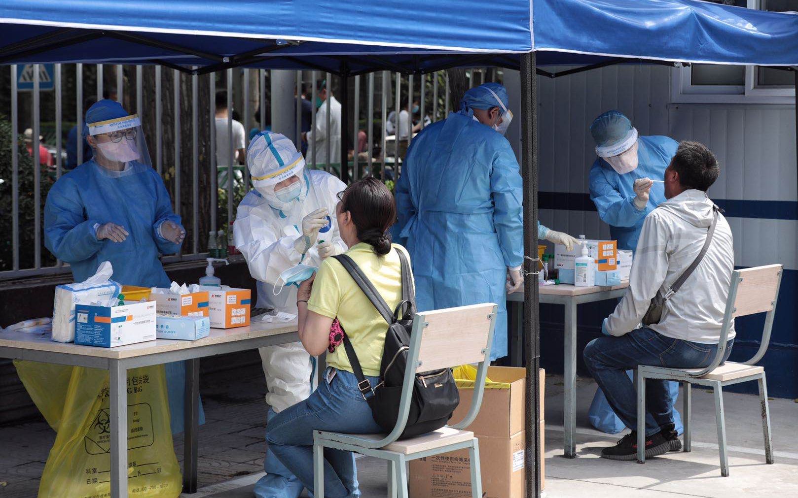 6月16日,北京世纪坛医院核酸检测采样点,工作人员为市民进行核酸采样