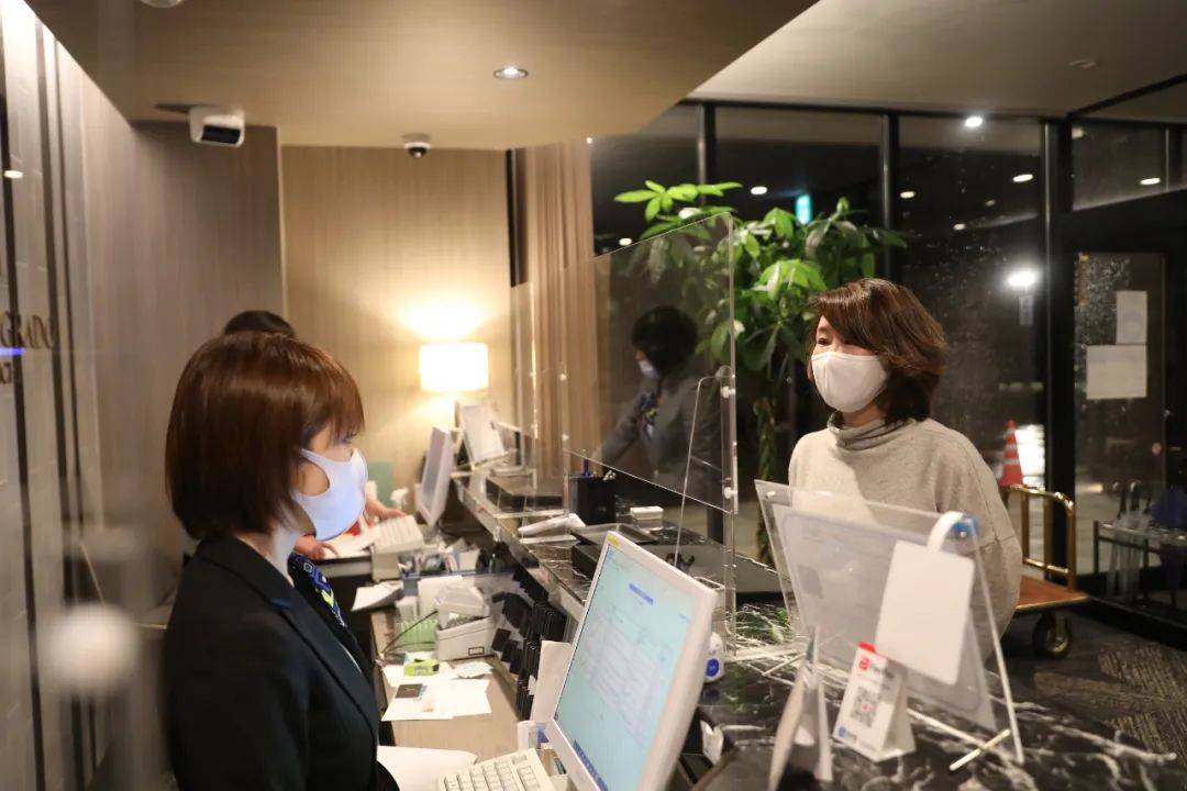 在日本福岛县相马郡,韩秋月(右)在温泉酒店询问前台工作人员营业情况