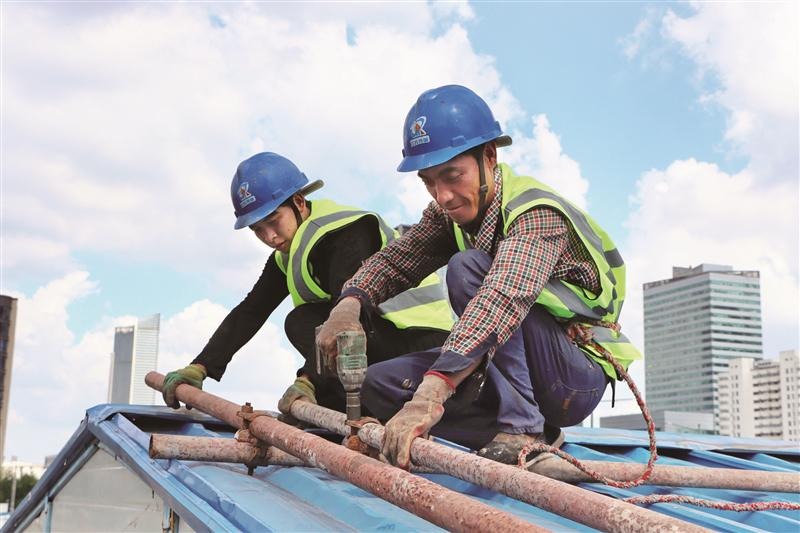 23日,在滴翠路太湖智谷建築工地生活區,工人在用鋼管加固臨時工棚.