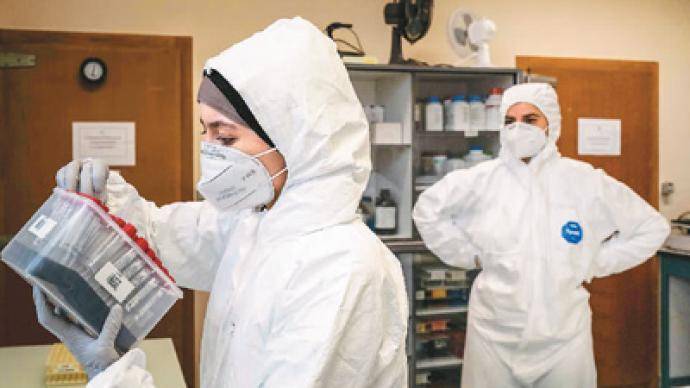 10月12日,在法国马西埃图瓦勒一所学校,实验人员检验新冠病毒检测样本